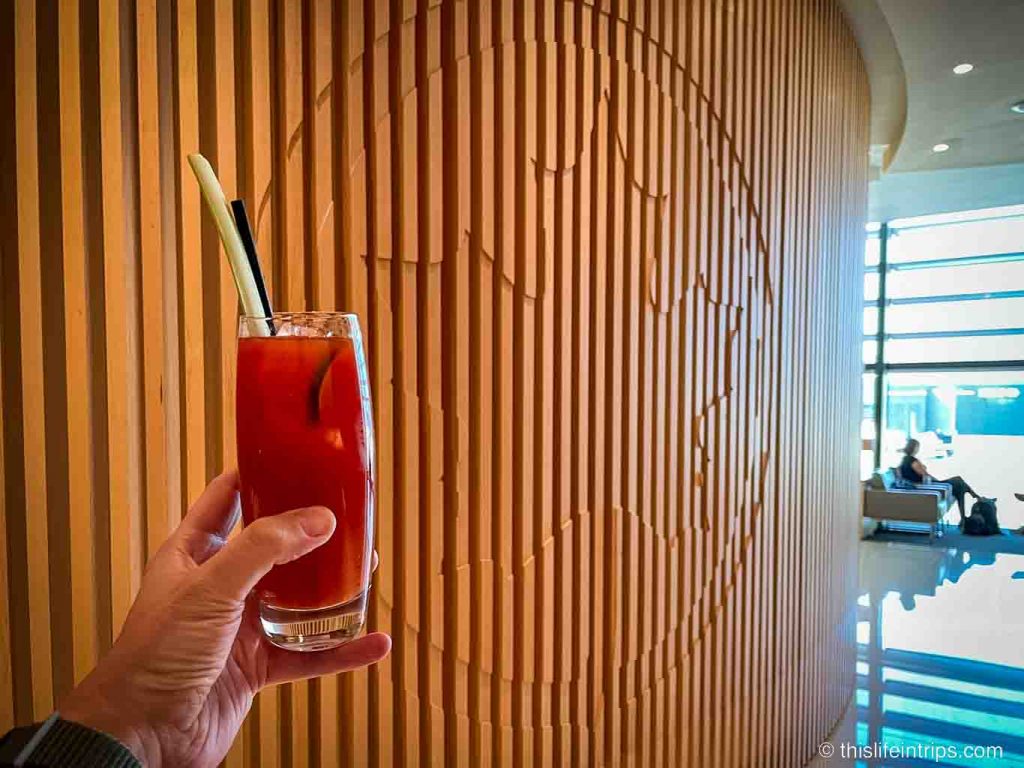 Hand holding up a Caesar at the Air Canada Maple Leaf Lounge Heathrow