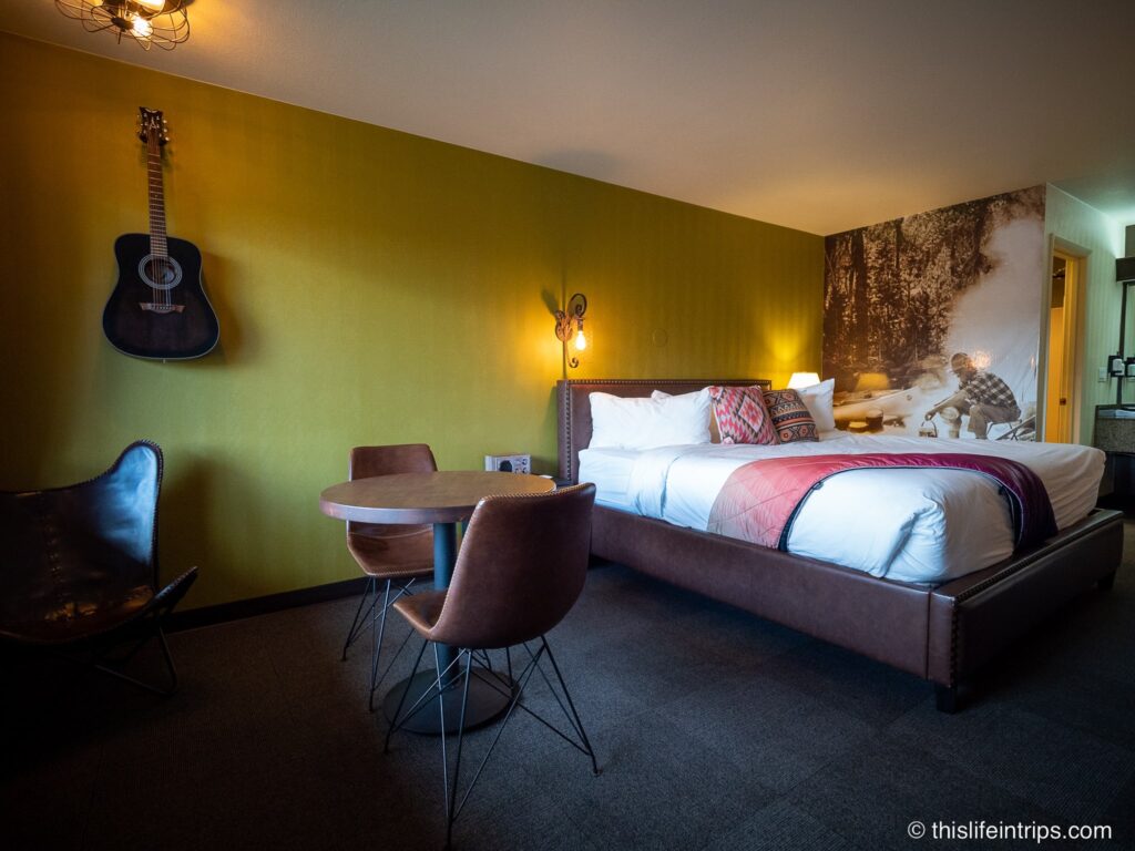 wide shot of campre fire hotel king room with acoustic guitar hanging on the wall