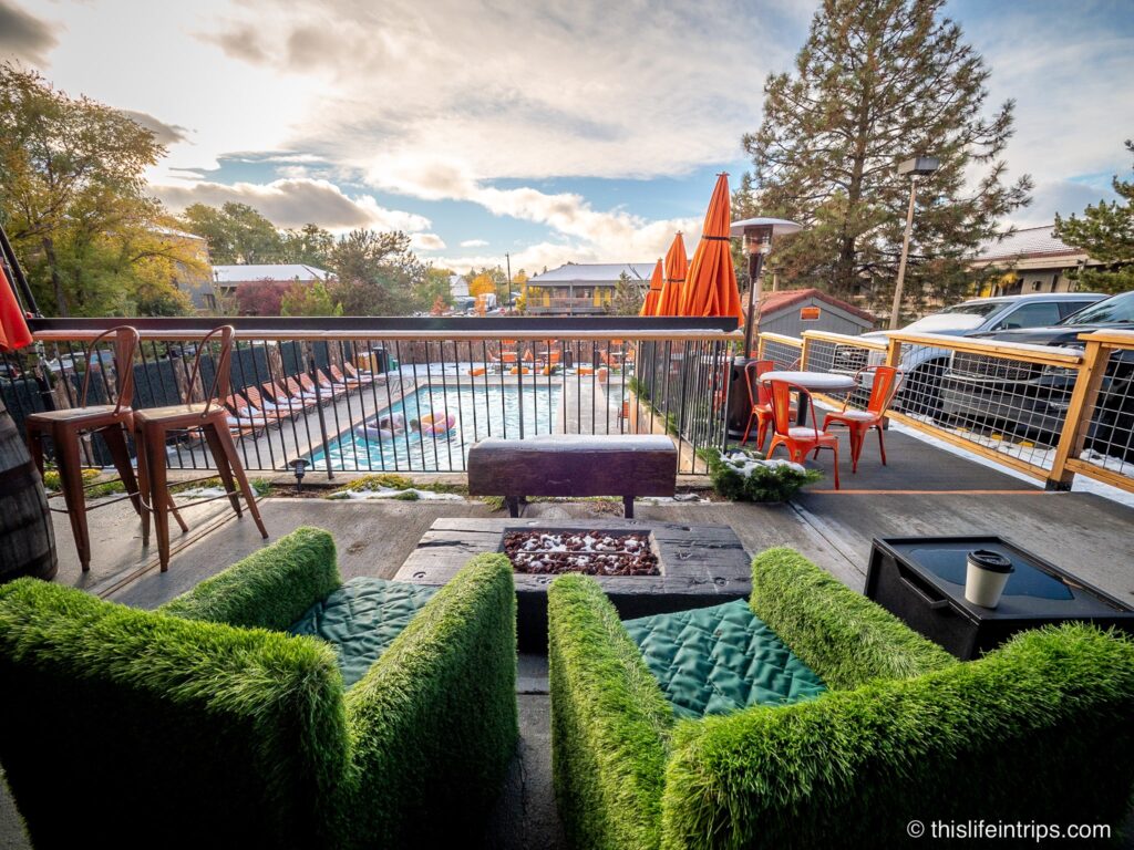 two chairs made of artificial grass in front of gas fireplace overlooking the pool at the Campfire Hotel