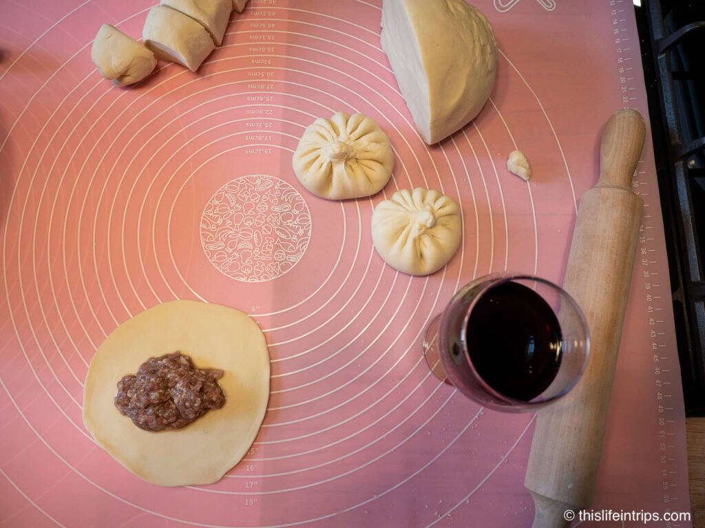 top down shot of two formed kninkali next to a wine glass