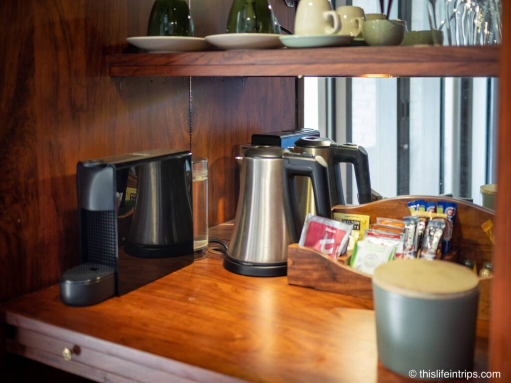 Table of coffee machine and tea kettle with cups and saucers.