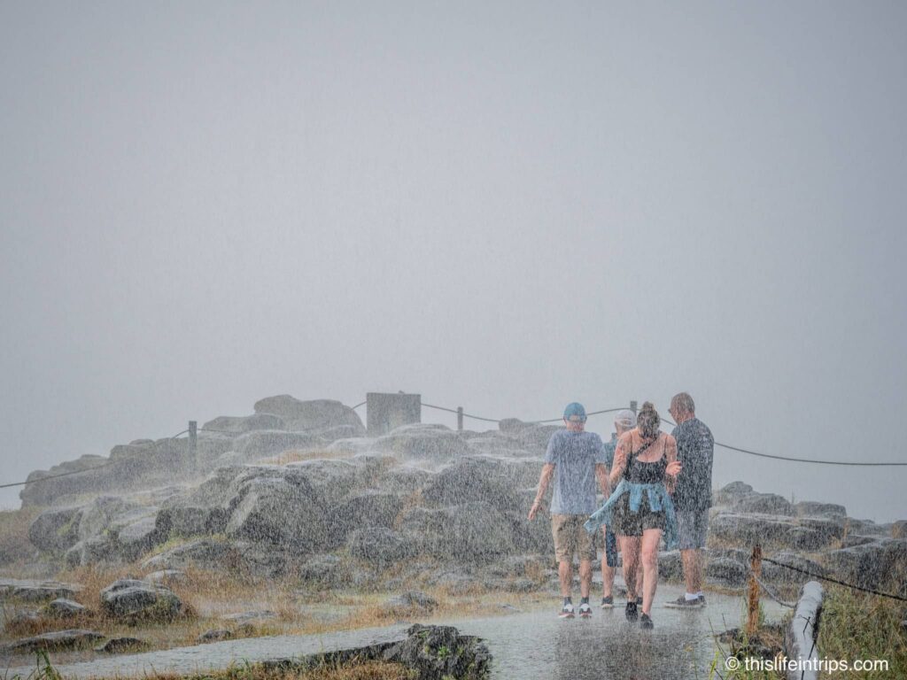 Woman and two men getting caught in the heavy rain produced by Victoria Falls.