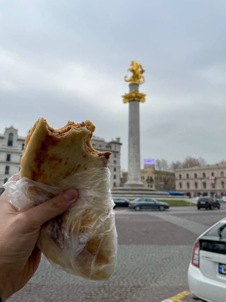 hand holding up half eaten Lobiani on the streets of Tbilisi