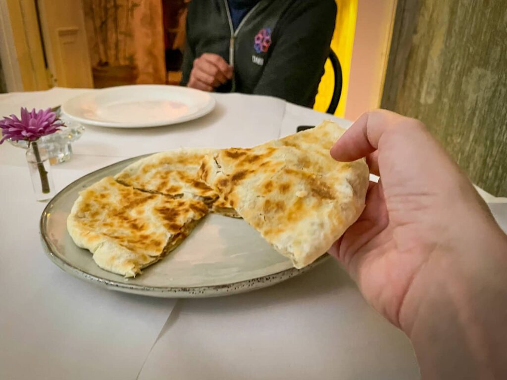 Hand hoding up a slice of Lobiani at a resturaunt