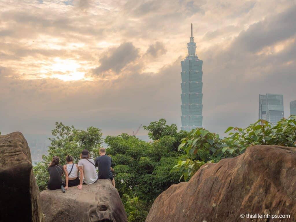 4 people sitting on a boulder Waiting for sunset after an Elephant mountain Taipei hike