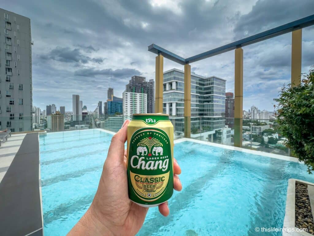 Rooftop pool hand holding up Chang beer at Staybridge Suites Bangkok Thonglor